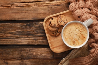 Photo of Flat lay composition with cup of coffee and knitted sweater on wooden table, space for text. Cozy winter