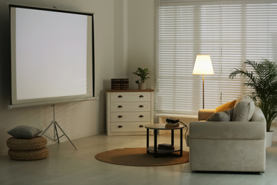 Photo of Stylish room with modern video projector and comfortable sofa