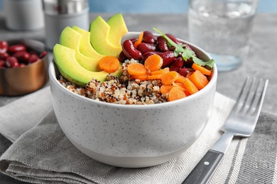 Photo of Healthy quinoa salad with vegetables in bowl served on table