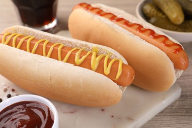 Photo of Tasty hot dogs with mustard and ketchup on wooden table, closeup