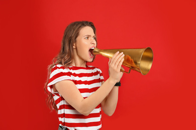 Photo of Young woman with megaphone on red background