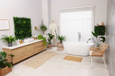 Green artificial plants, vanity and tub in bathroom