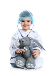 Cute child playing doctor with stuffed toy on white background