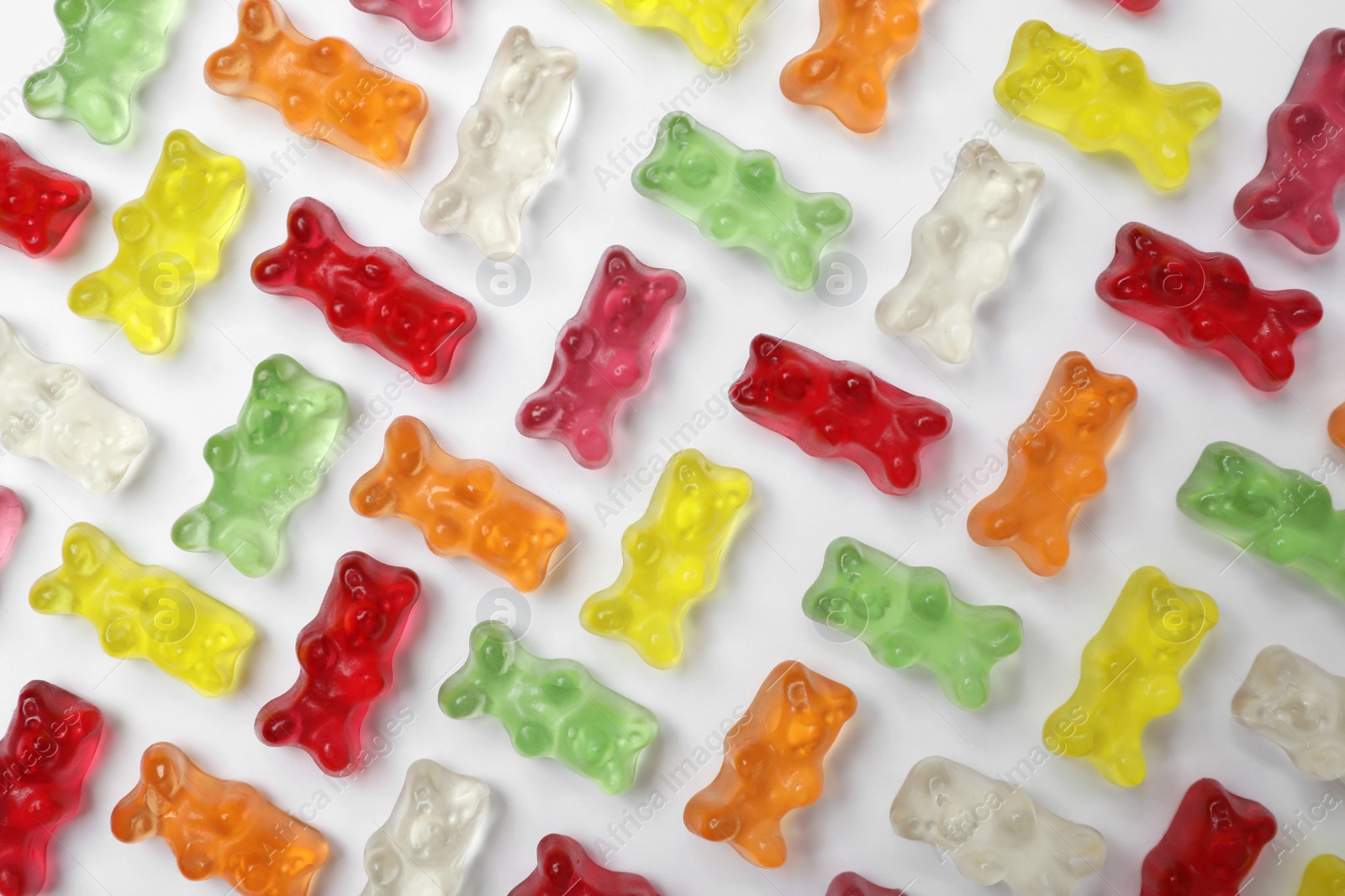 Photo of Many delicious little jelly bears on white background, top view