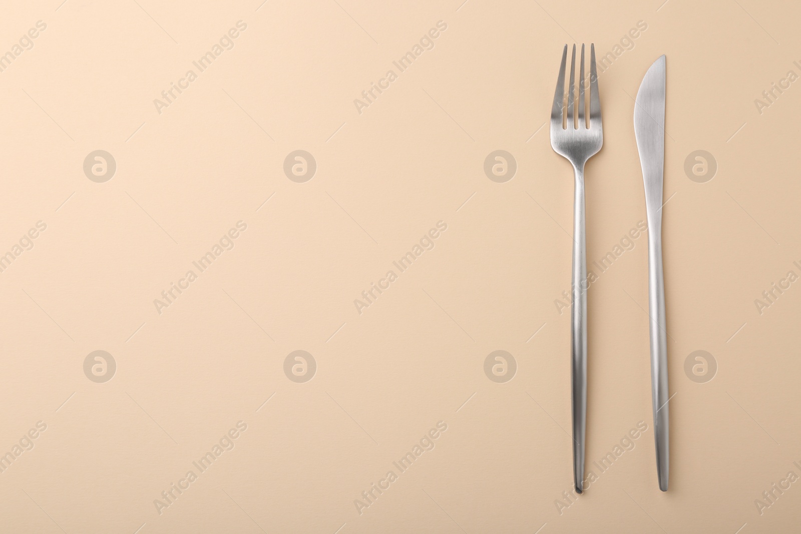 Photo of Stylish cutlery on beige table, top view. Space for text