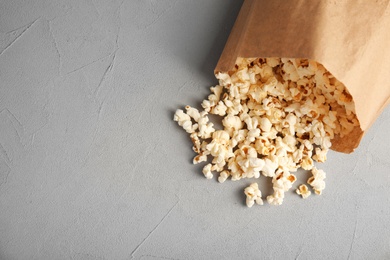 Paper bag with tasty popcorn on grey background, top view