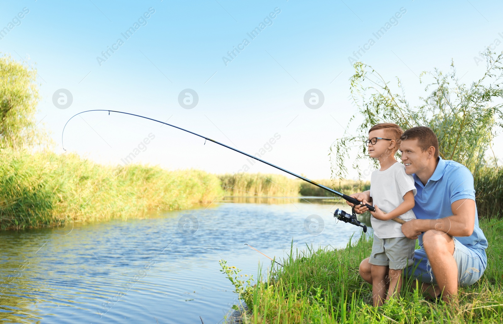 Photo of Dad and son fishing together on sunny day