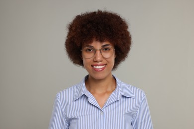 Photo of Portrait of happy young woman in eyeglasses on grey background