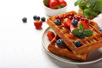 Photo of Delicious Belgian waffles with berries served on white wooden table. Space for text