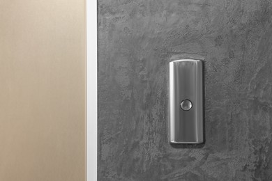 Elevator call button on grey textured wall