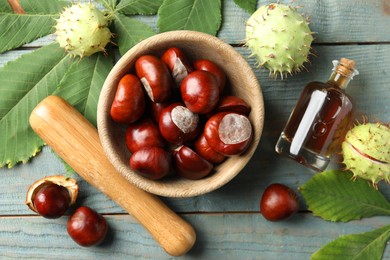 Photo of Mortar with pestle, chestnuts and essential oil on blue wooden table, flat lay