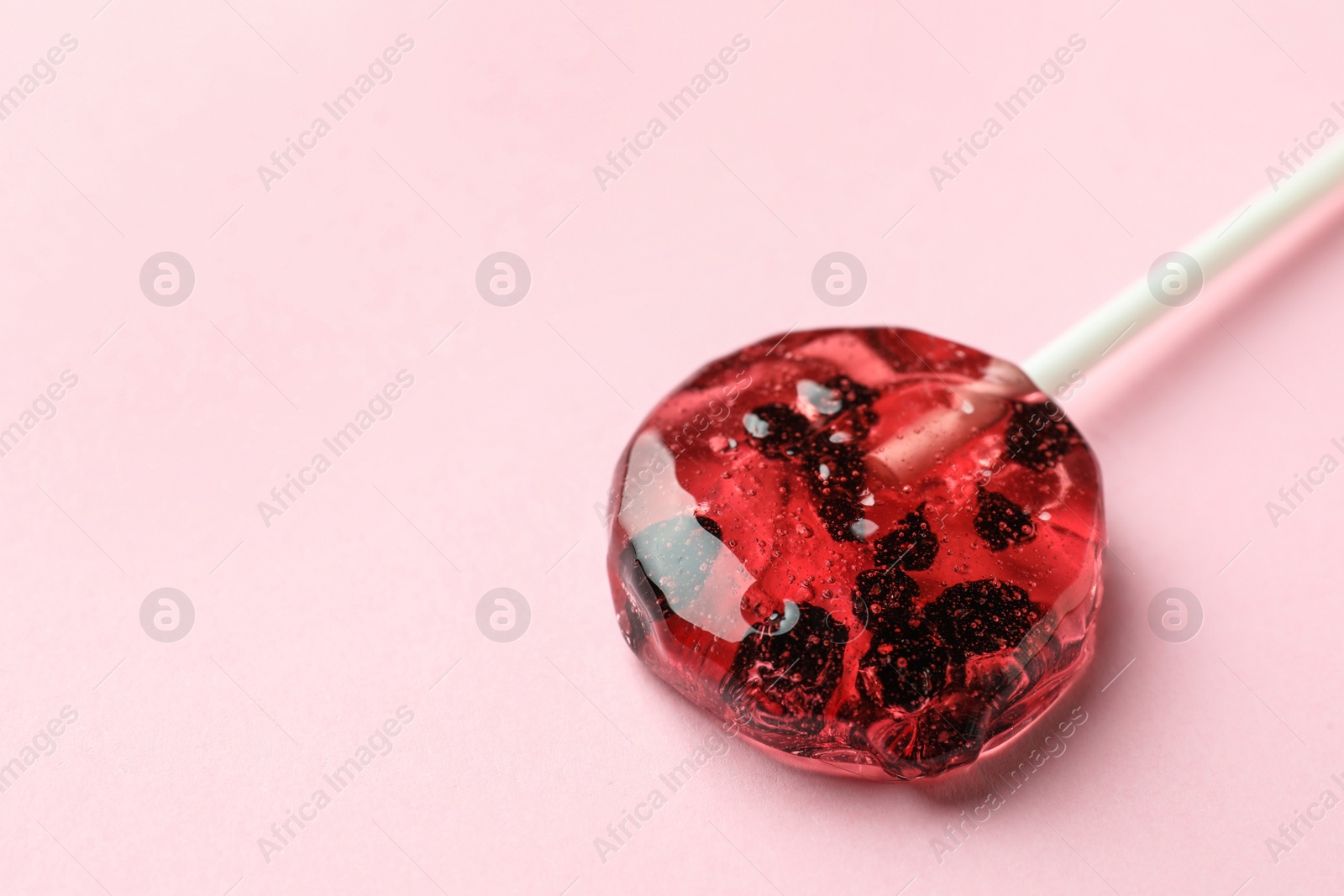 Photo of Sweet colorful lollipop with berries on pink background, closeup. Space for text
