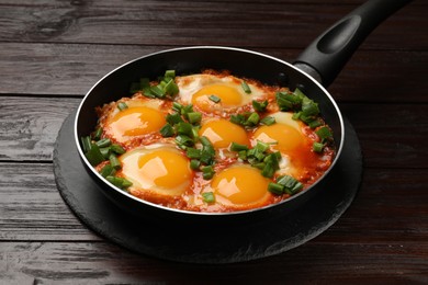 Photo of Delicious shakshuka in frying pan on wooden table, closeup