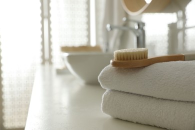 Photo of Stack of clean towels and massage brush on countertop in bathroom. Space for text