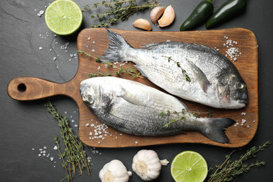 Photo of Flat lay composition with raw dorada fish on black table