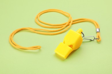One yellow whistle with cord on light green background