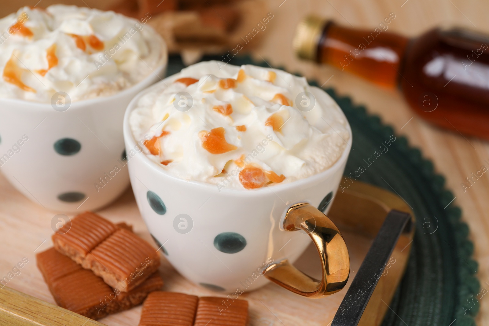 Photo of Delicious coffee with whipped cream and caramel syrup on table, closeup