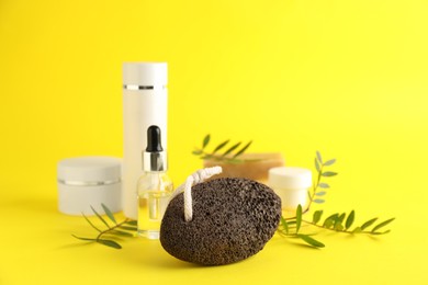 Pumice stone and cosmetic products on yellow background