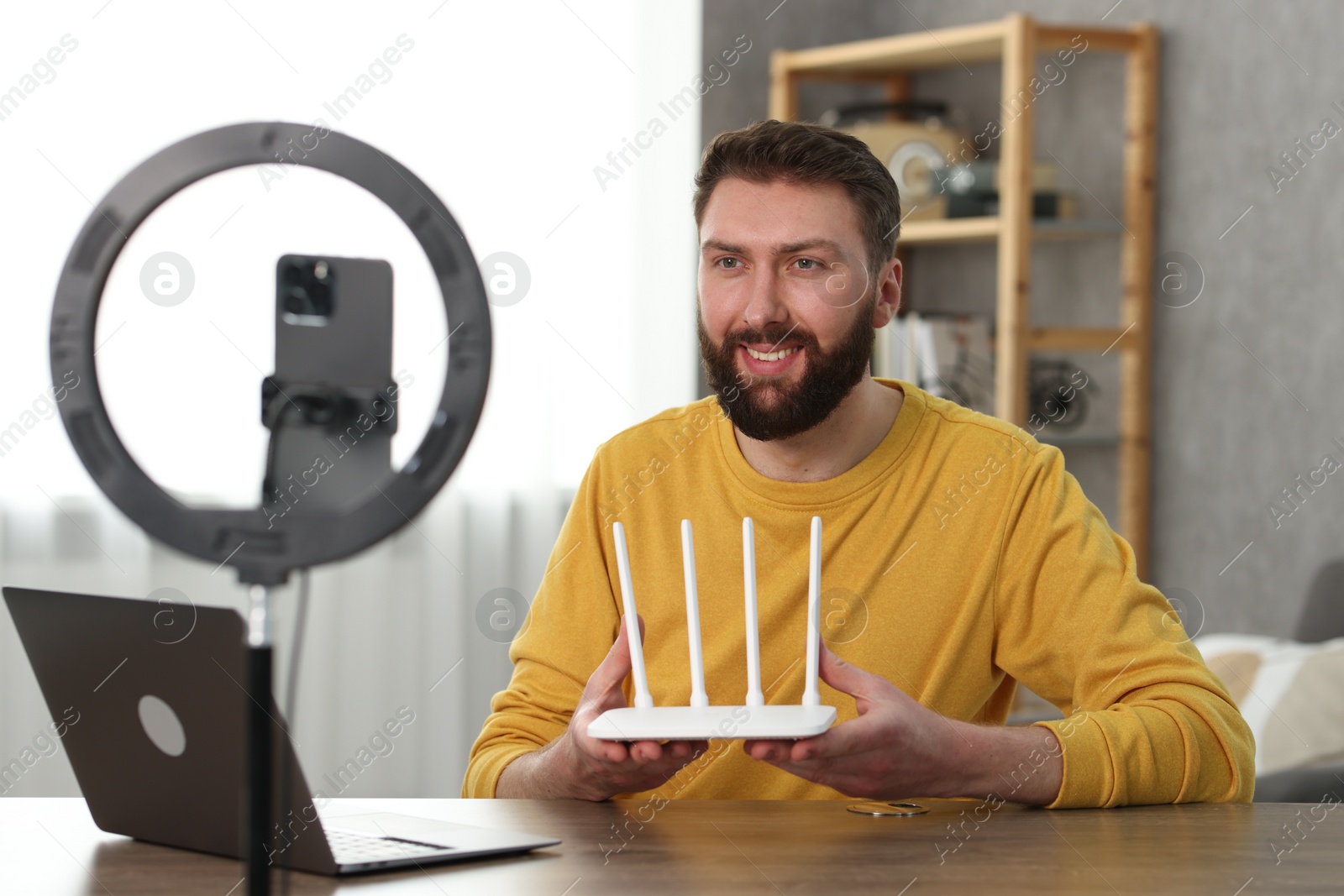 Photo of Smiling technology blogger recording video review about WI-FI router at home