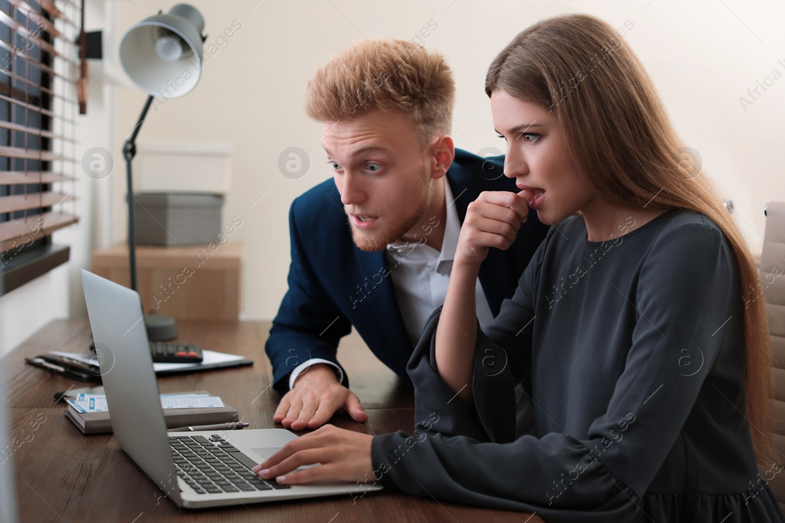 Photo of Concentrated young people playing online lottery using laptop at table in office