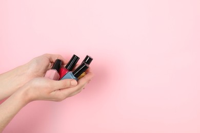 Photo of Woman holding nail polishes on pink background, closeup. Space for text