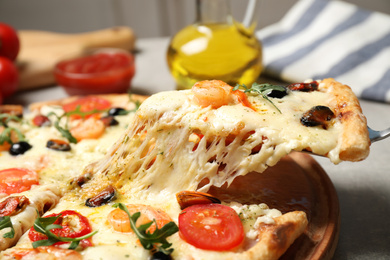 Photo of Taking slice of cheese pizza with seafood at table, closeup