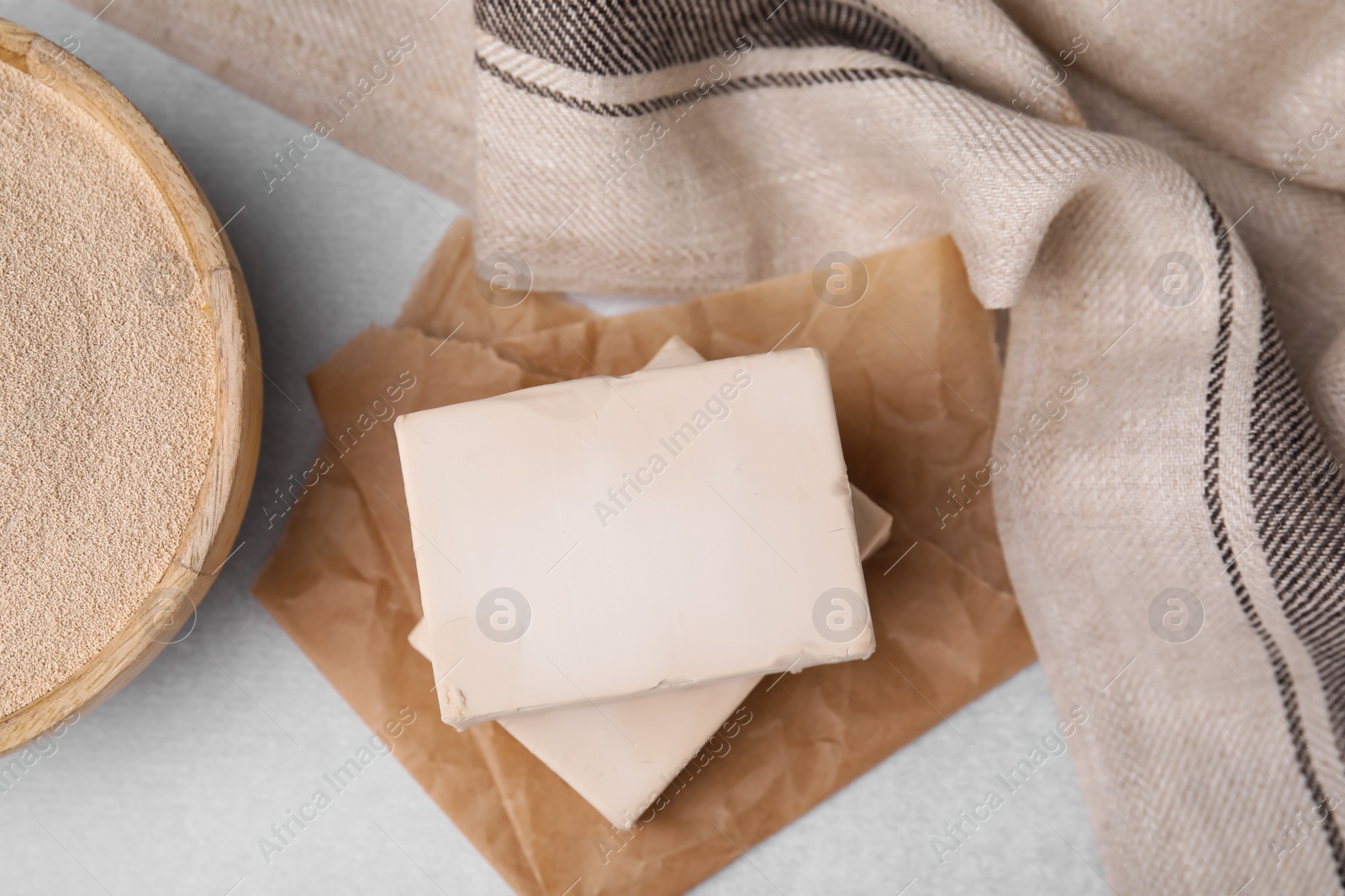 Photo of Compressed and granulated yeast on light gray table, flat lay