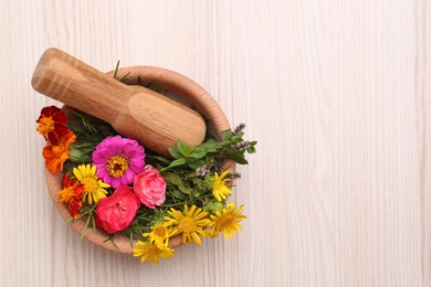 Photo of Mortar with pestle and beautiful fresh flowers on wooden table, top view. Space for text