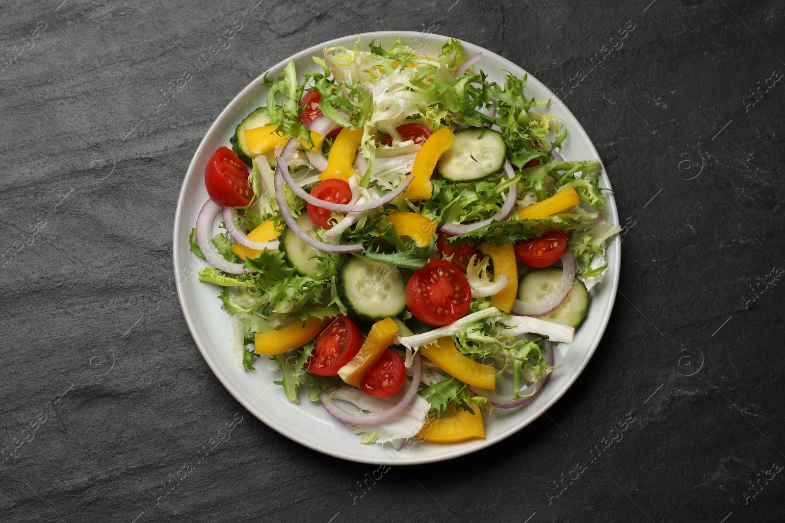 Photo of Tasty fresh vegetarian salad on black table, top view