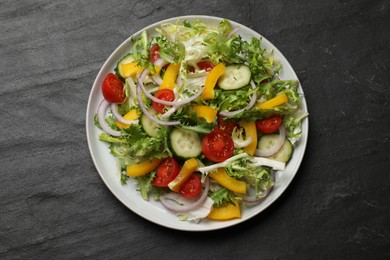 Photo of Tasty fresh vegetarian salad on black table, top view