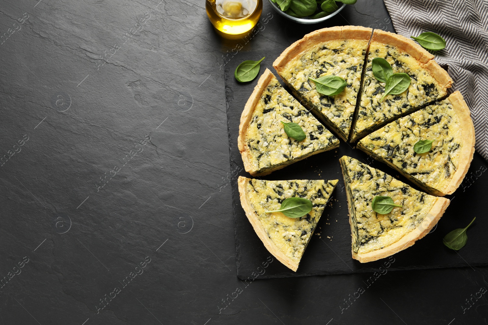 Photo of Cut delicious spinach pie on black table, flat lay. Space for text