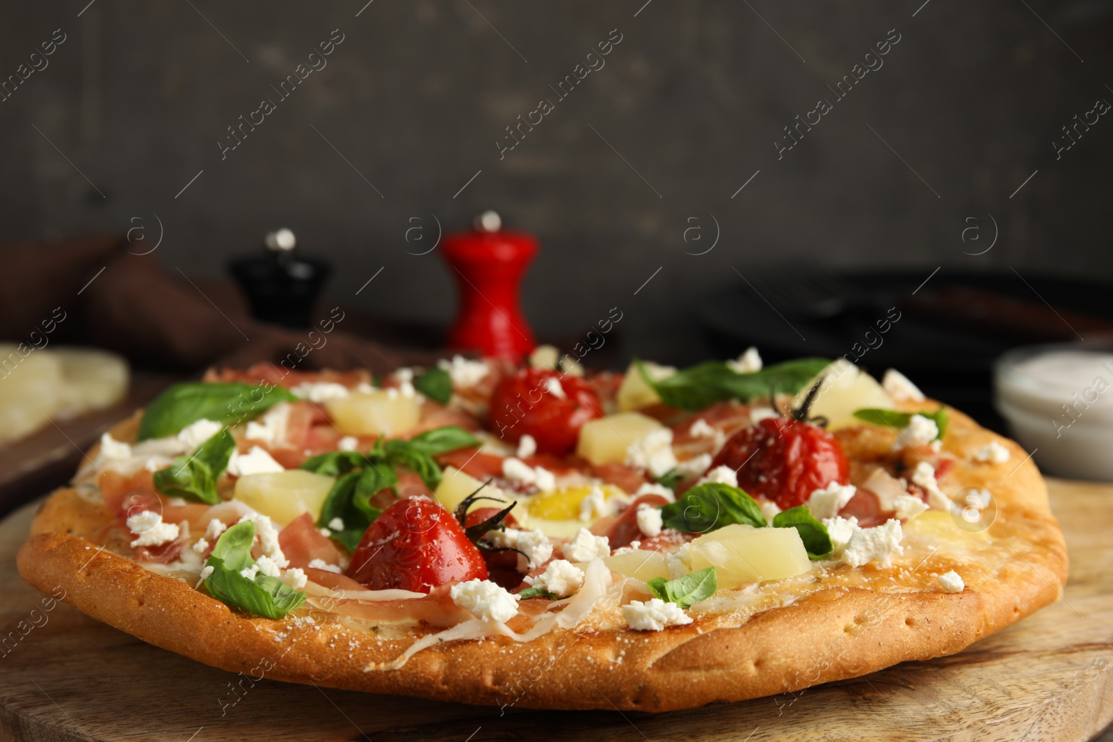 Photo of Pita pizza with prosciutto, pineapple, grilled tomatoes and egg on wooden table, closeup