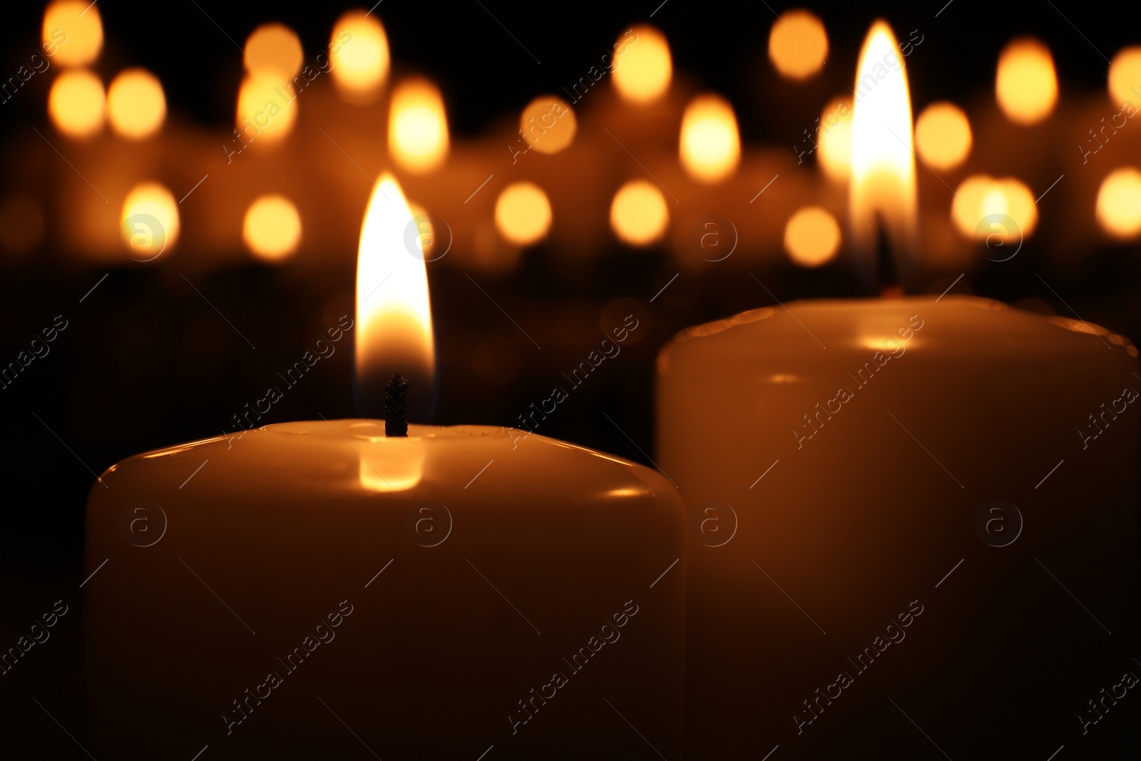 Photo of Burning candles in darkness, closeup. Memory day