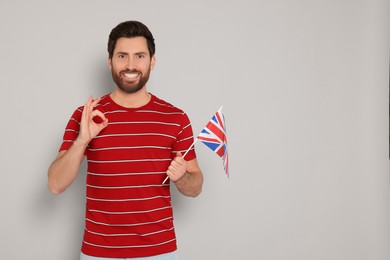 Man with flag of United Kingdom showing ok gesture on light grey background, space for text