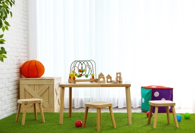 Stylish playroom interior with toys and modern wooden furniture