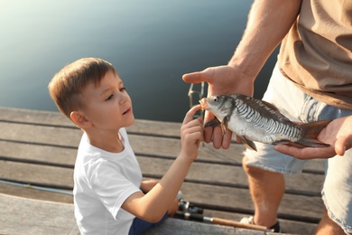 Photo of Dad and son holding caught fish at lake