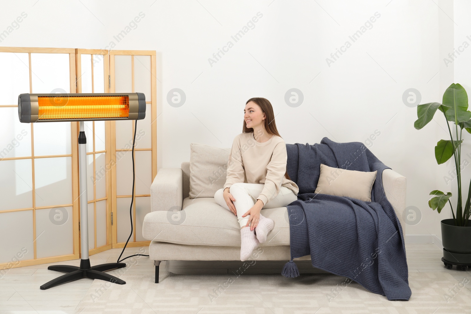 Photo of Woman warming near electric infrared heater indoors