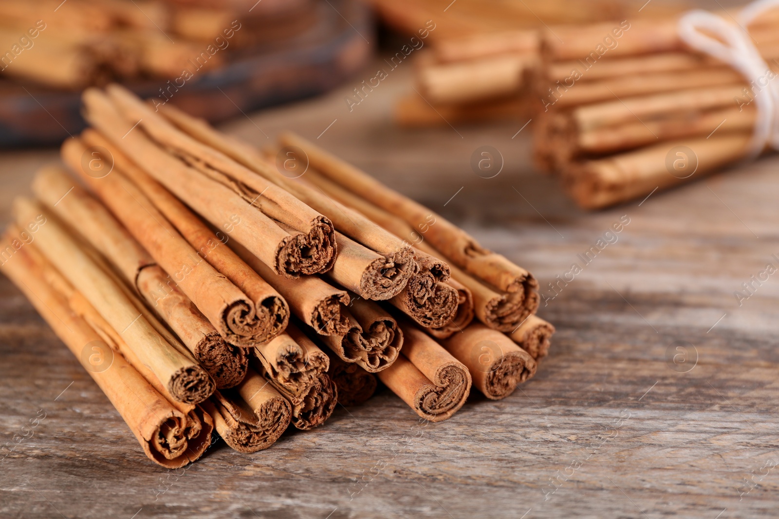 Photo of Aromatic cinnamon sticks on wooden table, closeup