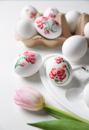 Painted Easter eggs and tulip on white table