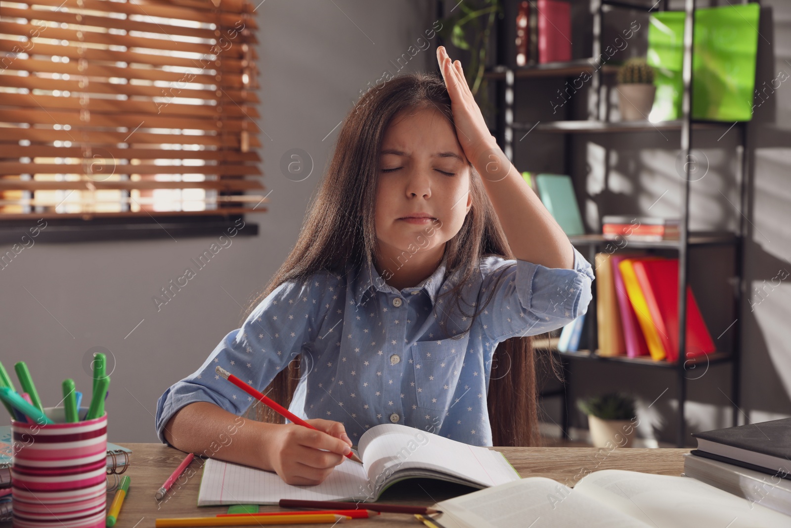 Photo of Tired preteen girl at table. Doing homework