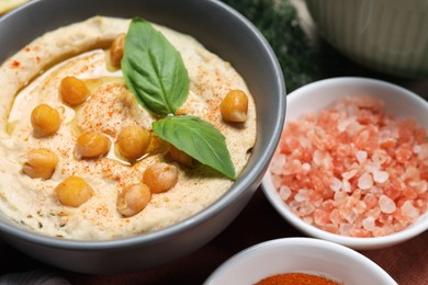 Delicious creamy hummus with chickpeas and ingredients on table, closeup