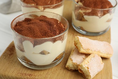Photo of Delicious tiramisu in glasses and cookies on table, closeup