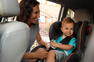 Photo of Woman fastening her son with car safety belt. Family vacation