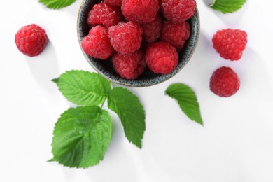 Photo of Tasty ripe raspberries and green leaves on white background, flat lay