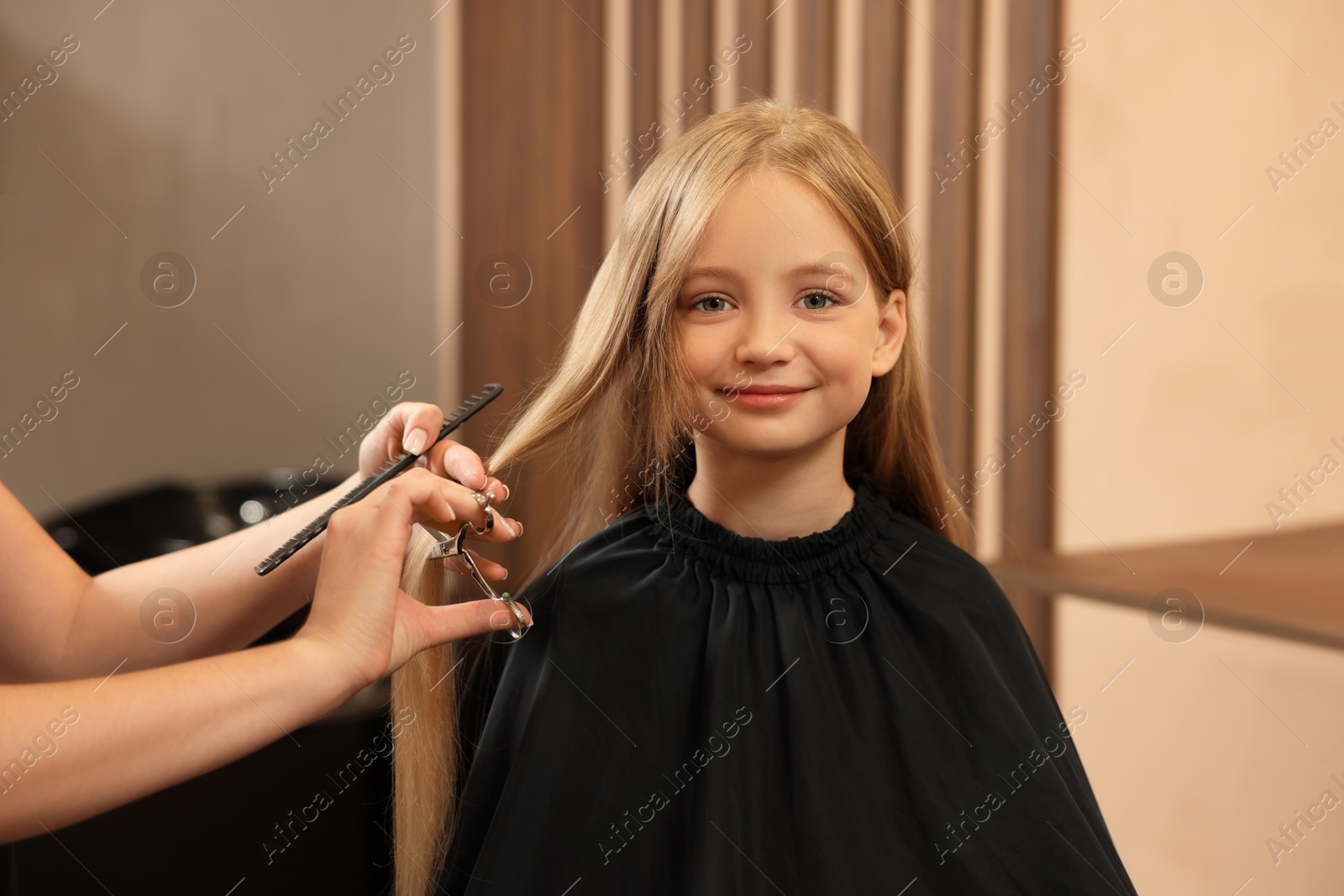 Photo of Professional hairdresser cutting girl's hair in beauty salon