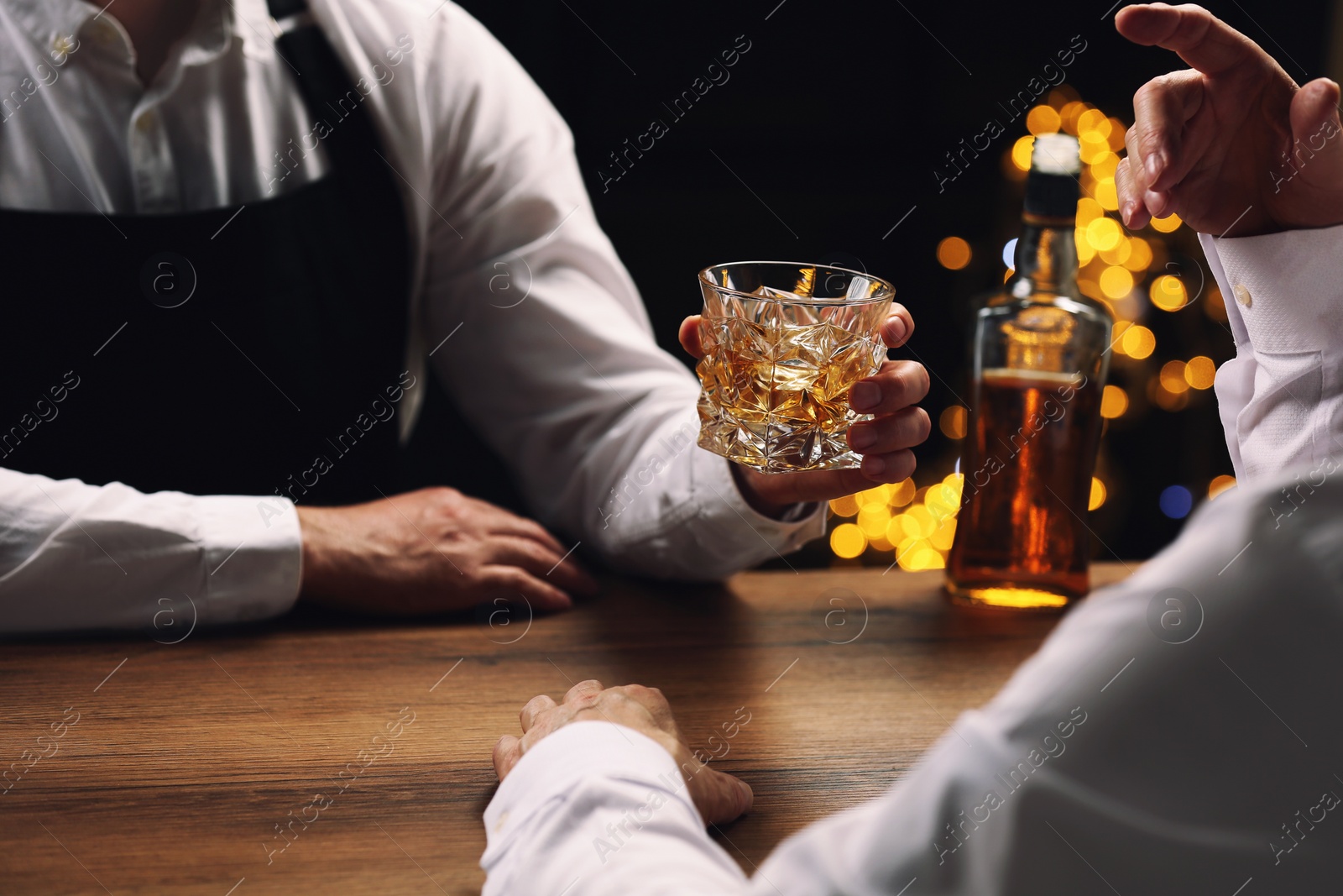 Photo of Bartender giving glass of whiskey to customer at bar counter, closeup