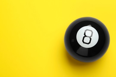 Photo of One magic eight ball on yellow background, top view. Space for text
