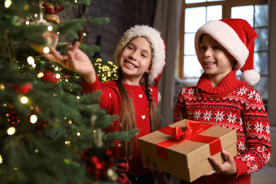 Cute children near beautiful Christmas tree at home