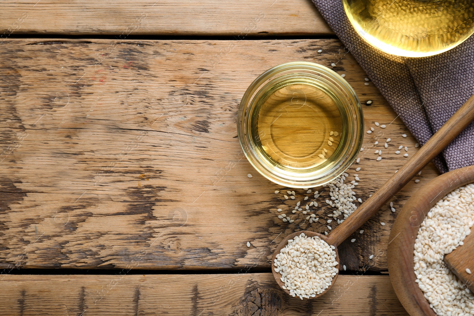 Photo of Sesame oil and seeds on wooden table, flat lay. Space for text