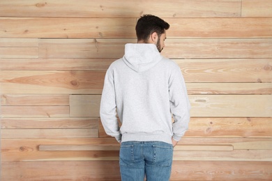 Photo of Young man in sweater at wooden wall. Mock up for design